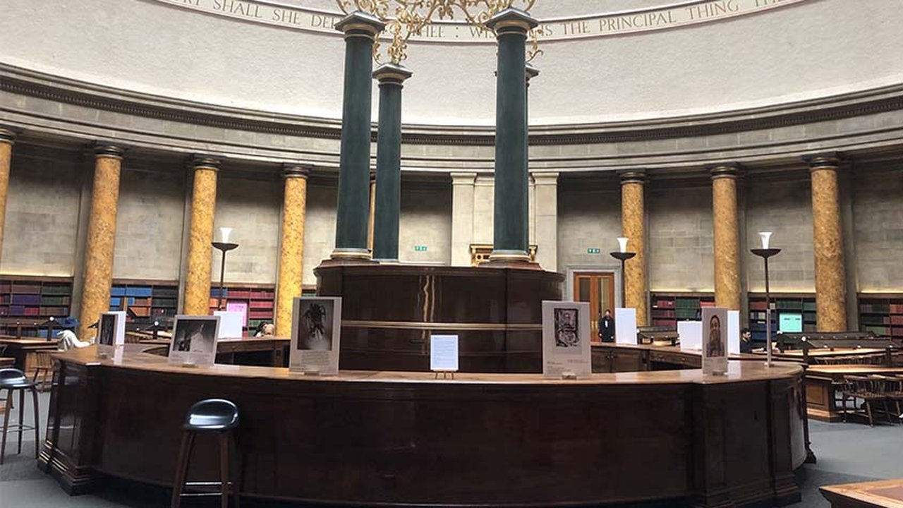 The image shows the students' work on display in the Wolfson Reading Room at Manchester Central Library.