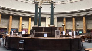 The image shows the students' work on display in the Wolfson Reading Room at Manchester Central Library.