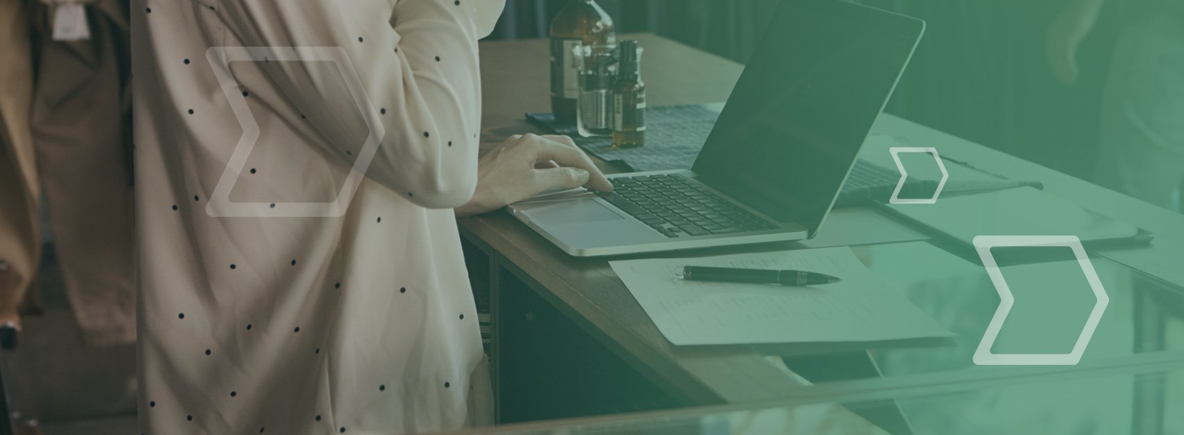 A person standing at a desk working on a laptop