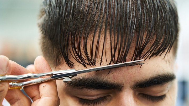 Close up of a man getting his haircut with scissors