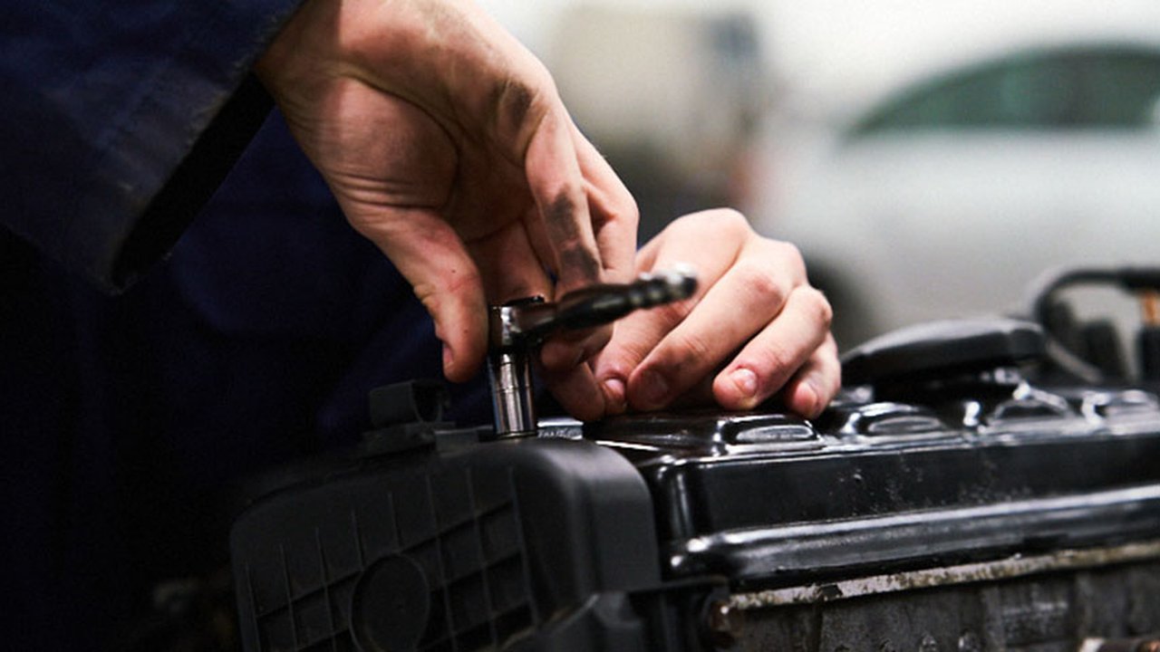 Photograph of a student at The Manchester College working with a car part.