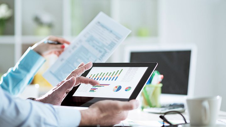 Man holding an iPad with accounting graphs and tables on it