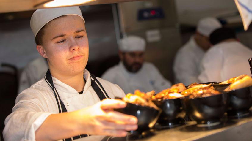 A catering student serving freshly prepared food