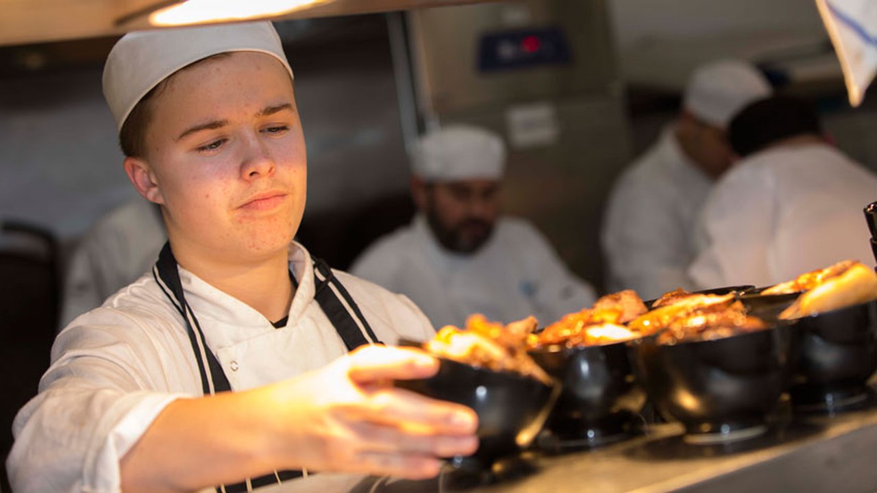 A catering student serving freshly prepared food