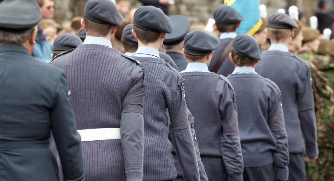 Group of uniformed cadets standing in formation outdoors during a ceremonial event.