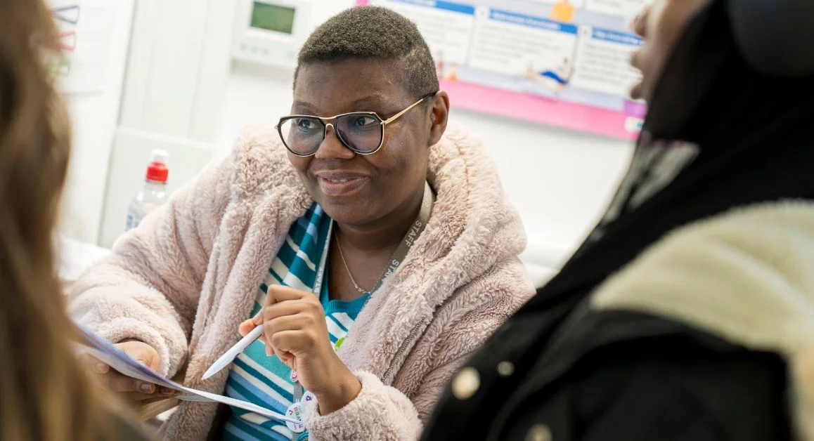 A staff member at The Manchester College providing information to students in a classroom setting