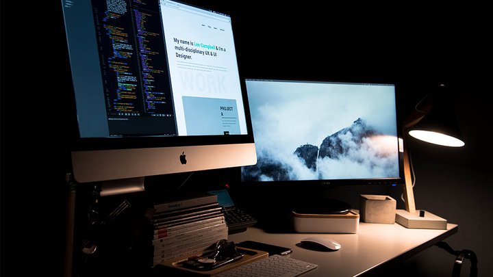 Two computers next to each other, one displaying JavaScript the other an interactive website