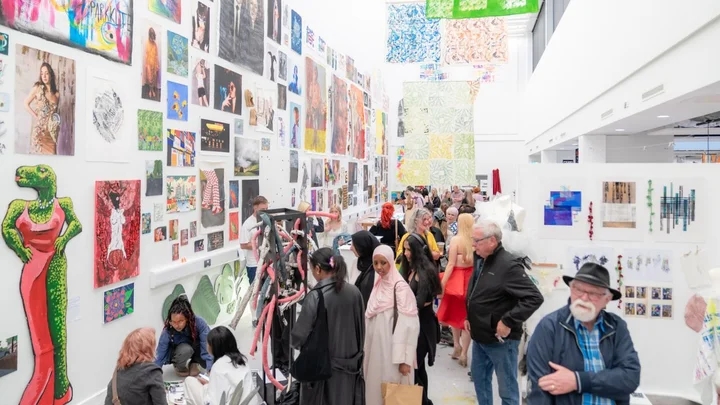 Visitors exploring a Visual Arts exhibition showcasing student artwork, prints, paintings and creative projects at The Manchester College City Campus Manchester.