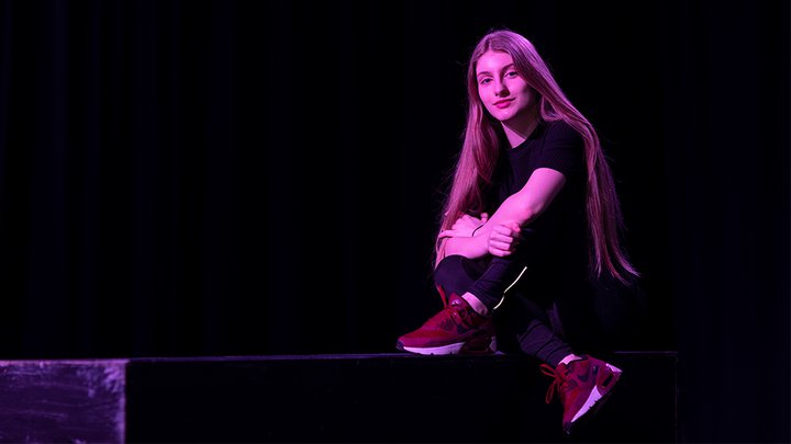 A student sat on the edge of a stage