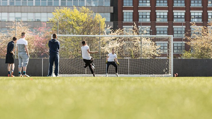 A small group of people playing football on an outdoor field