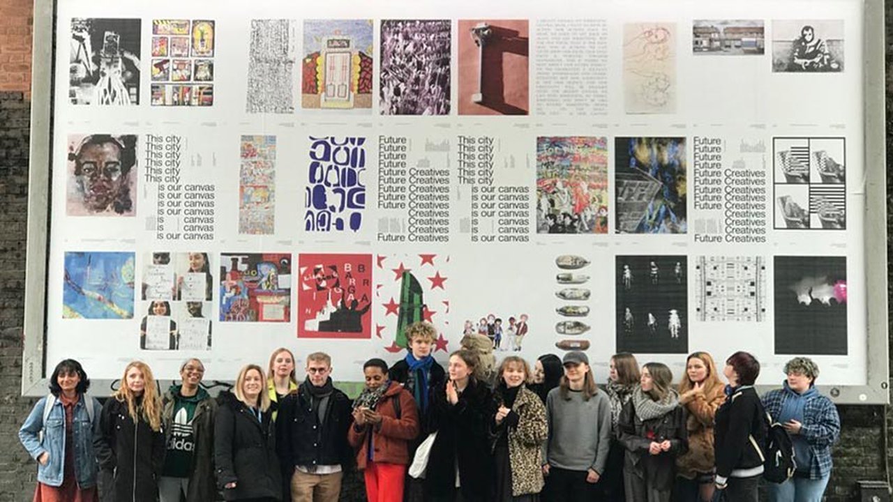 Design and Visual Arts students in front of a billboard showcasing their work