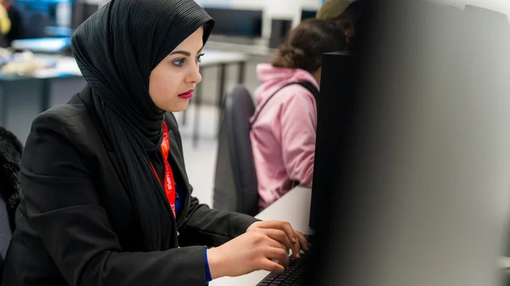 Person typing at a desktop computer during a focused classroom learning session.