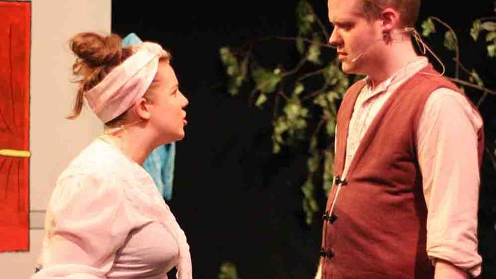 A female student facing a male student while they perform on stage