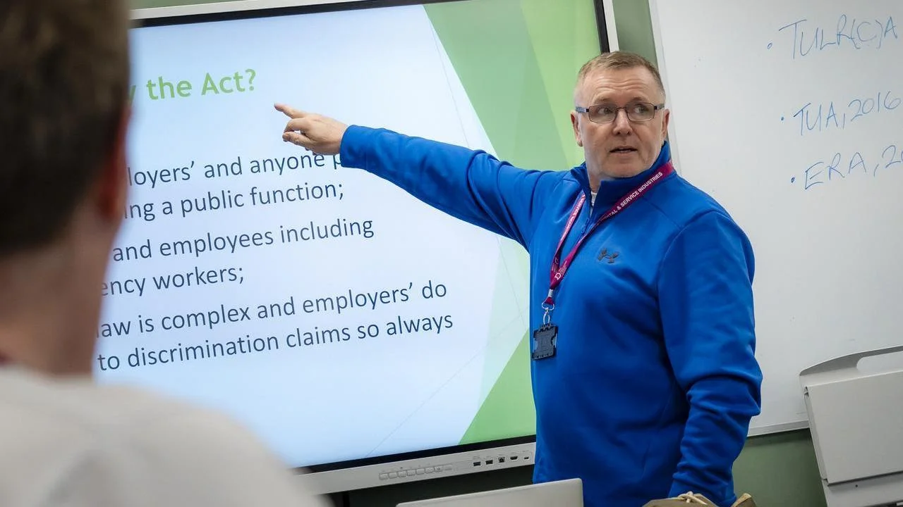 Training session with an instructor presenting workplace legislation and employment rights to learners in a classroom.