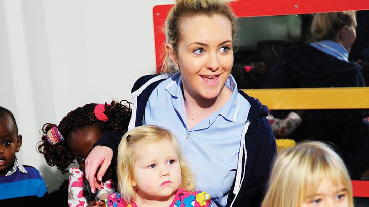 Image of a early years nursery practitioner looking after a group of children