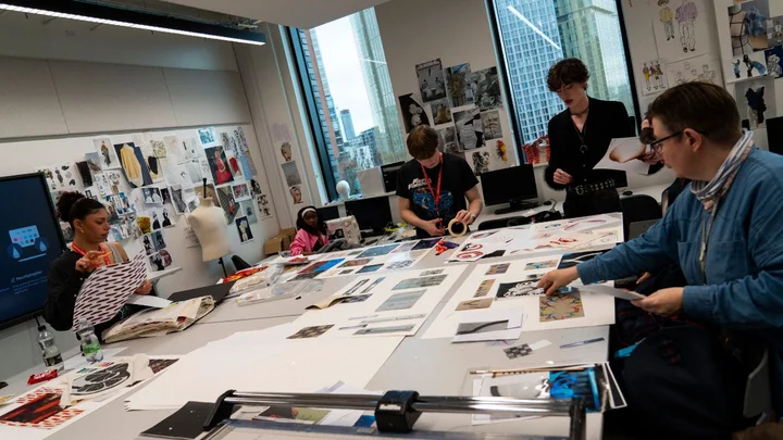 A fashion and textiles classroom where learners are creating design boards and cutting materials on large studio tables.