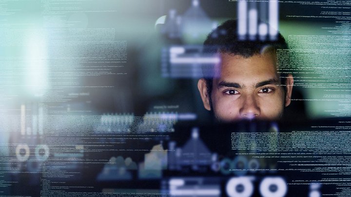 A man looking at a creen full of computer codes