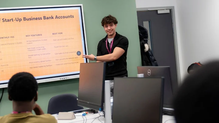 Person presenting business course content on a digital screen during a classroom learning session.