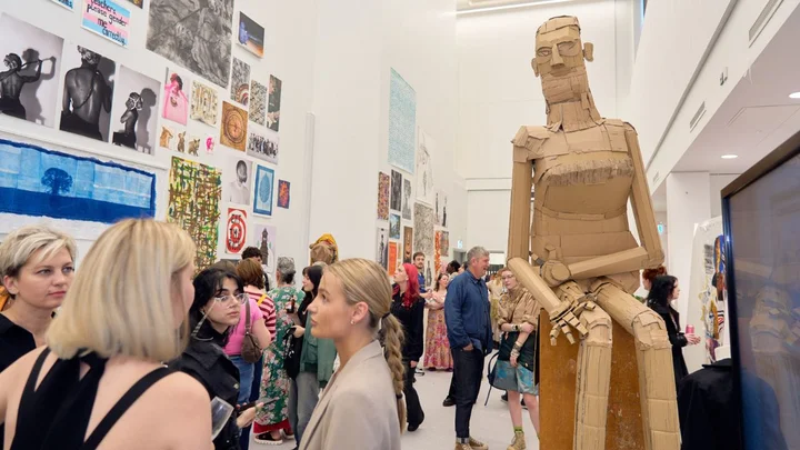 Visitors viewing large-scale student artwork and sculpture during a Visual Arts exhibition at The Manchester College City Campus Manchester.
