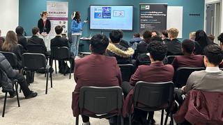 A picture taken from the back of the classroom of school children sat watching a talk from tutors at The Manchester College.