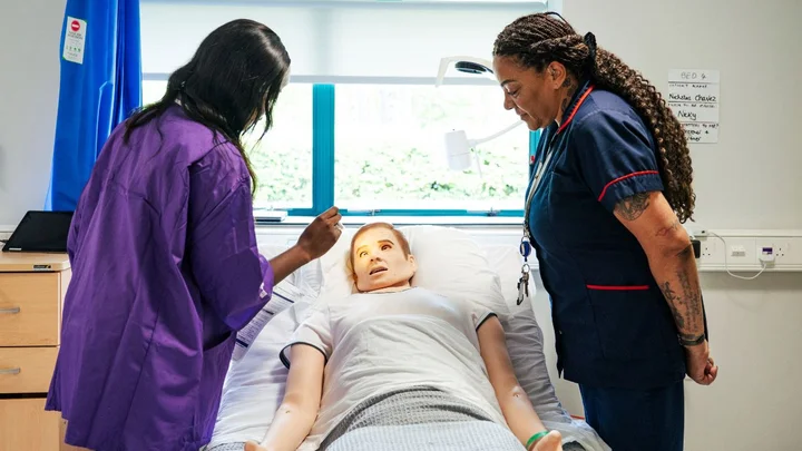Health and Social Care student developing clinical skills with a healthcare simulation mannequin in a realistic hospital training environment.
