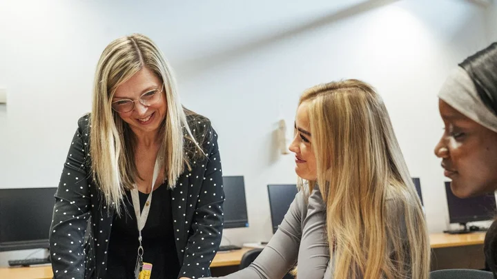 Health and Social Care tutor supporting students during a classroom learning session at The Manchester College.