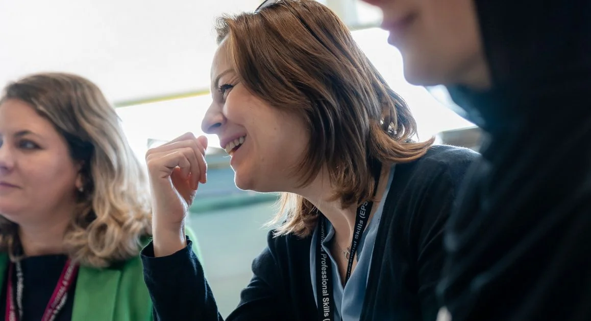 Several adults seated together and smiling during a classroom session at The Manchester College.