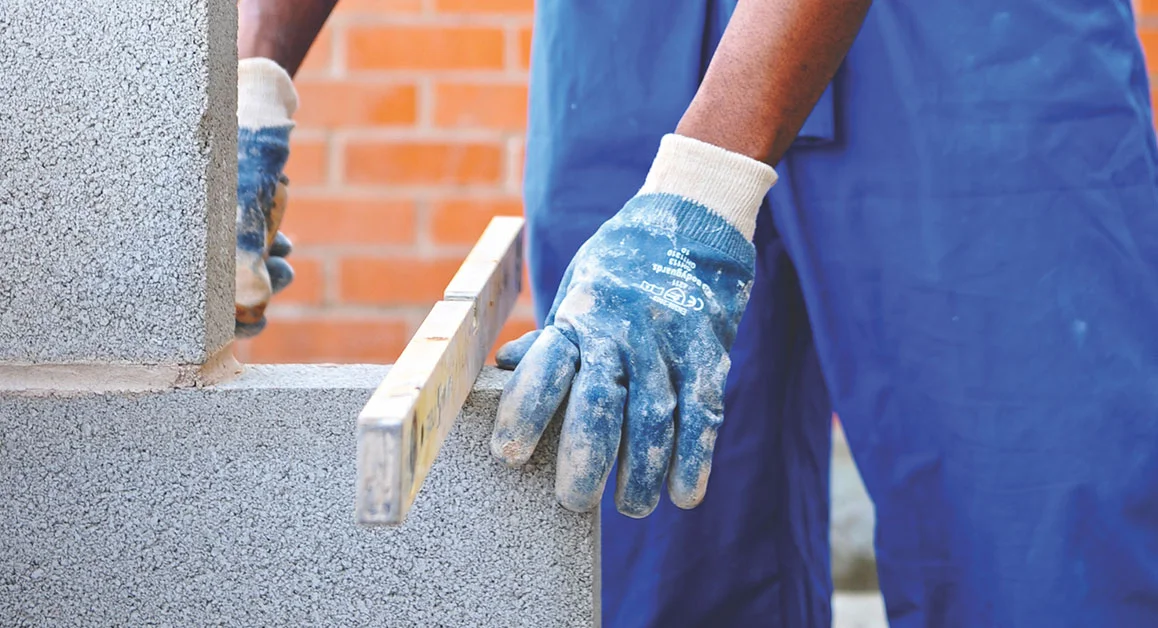 Construction worker aligning concrete blocks with a spirit level.