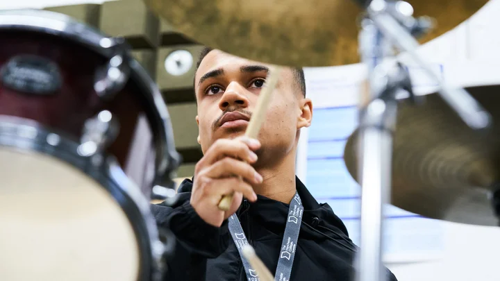 Student pictured through a drumkit mid-performance