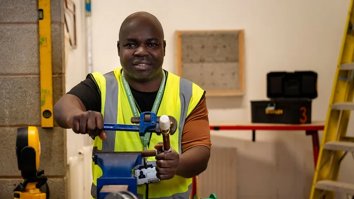 Student using hand tools at a workbench in a construction workshop at The Manchester College