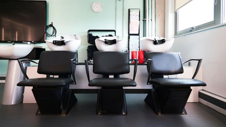 Hairdressing wash station with three backwash basins and salon chairs in a training salon.