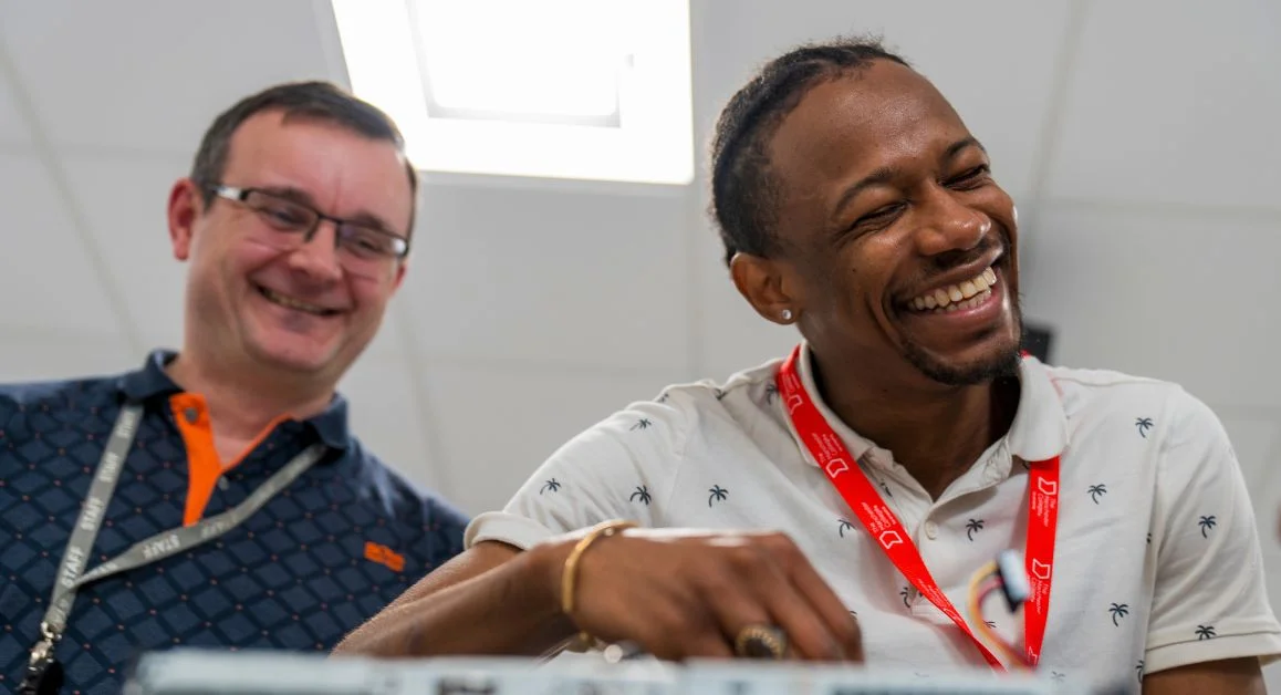 Higher education learner and teacher wearing lanyards working together on a computer in a classroom at The Manchester College.