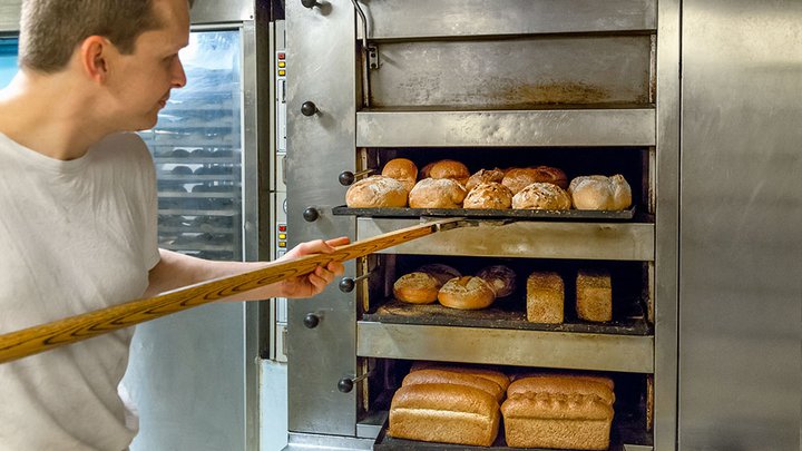 Freshly baked bread being taken out of a commrcial oven