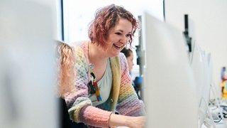 Photograph of a member of staff at The Manchester College talking to a student in a classroom setting.