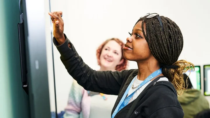 A learner using an interactive touchscreen during a creative and digital media session, engaging with digital tools in a classroom environment.