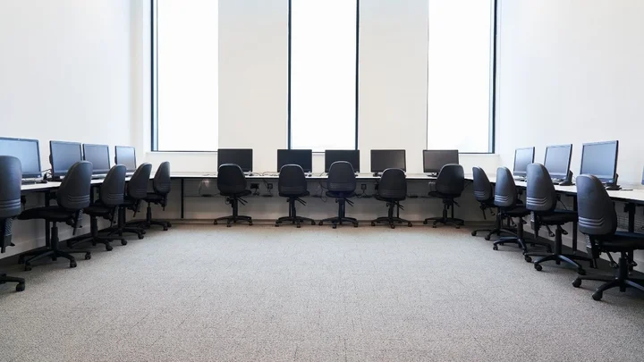 Computing learning space with desktop computer workstations arranged around the room, providing an open classroom layout for practical IT training.