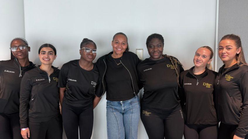 The Manchester College Sport students at the Women in Sport Conference, in front of a white wall.
