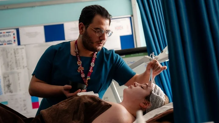 A beauty therapy learner performing a facial treatment during a practical training session in a salon classroom.