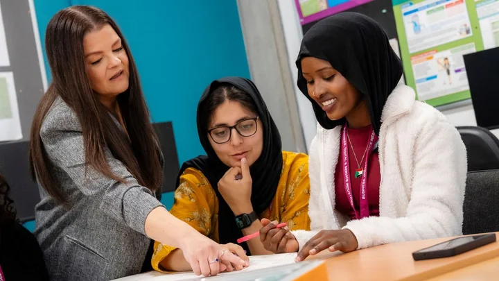 People working together at a table with documents and stationery during a collaborative business learning session.