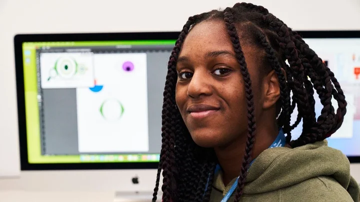 A learner working on a digital illustration project at a computer, with design software displaying eye graphics on the screen in a creative and digital media classroom.