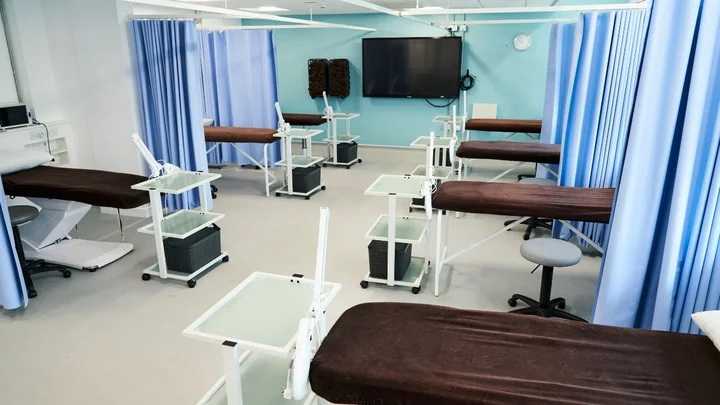 A beauty therapy training room with treatment beds, privacy curtains, and equipment stations neatly arranged.