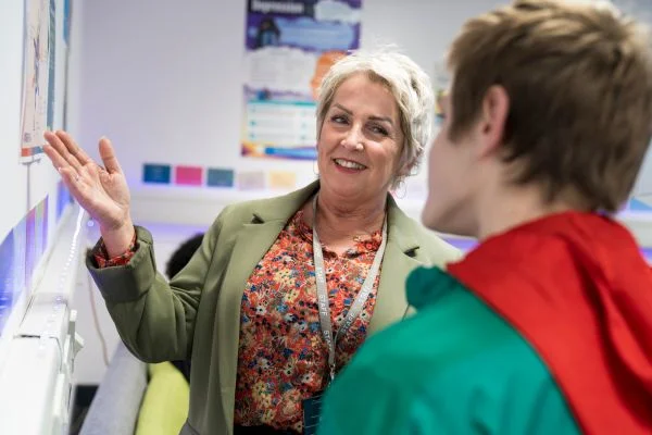 Staff member smiling and showing posters to a TMC student