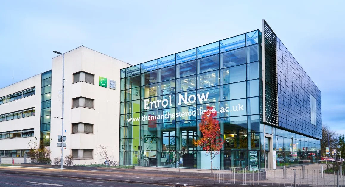 Exterior of The Manchester College Harpurhey Campus, showing a modern glass-fronted building connected to a white campus building.