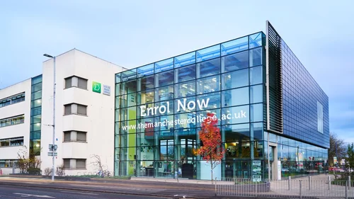 Exterior of The Manchester College Harpurhey Campus, showing a modern glass-fronted building connected to a white campus building.
