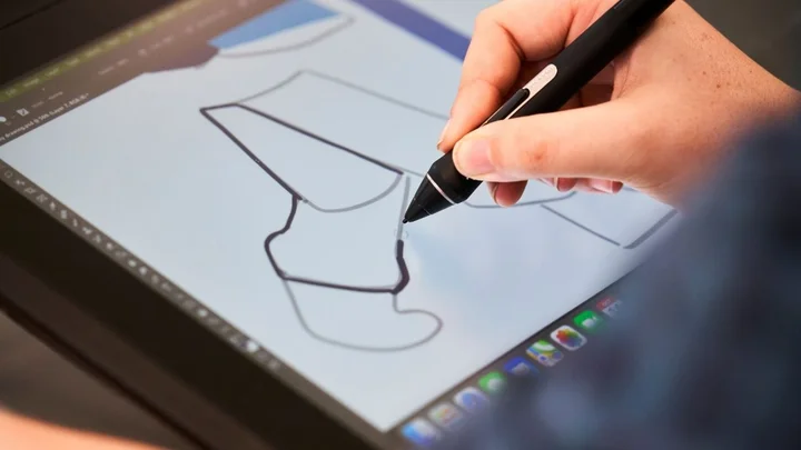 A learner using a digital pen to draw vector artwork on a graphics tablet during a creative and digital media session.