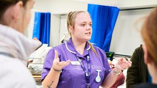 Health and social care student at The Manchester College talking to prospective students during an open event.