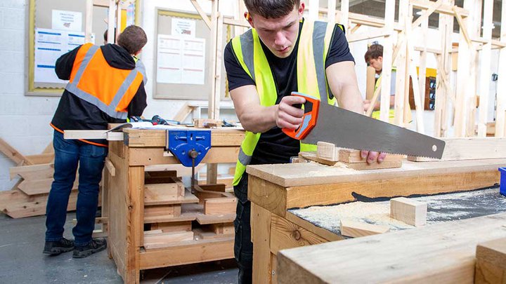 Student carpenter cutting a plank of wood