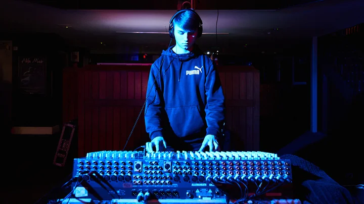 A student is stood over a DJ mixing table