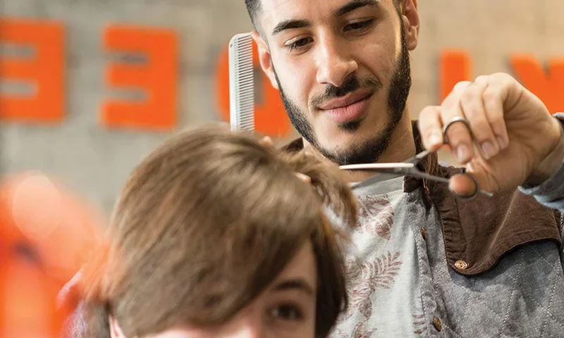 Hairdresser cutting a client’s hair with scissors and a comb.