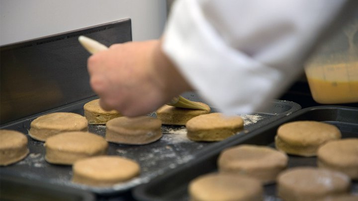 Freshly baked biscuits being glazed
